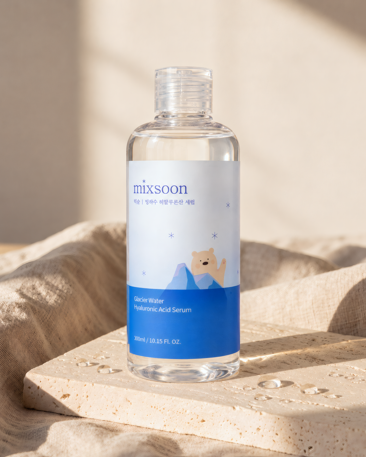 Mixsoon Glacier Water Hyaluronic Acid Serum on a stone block with linen and water droplets