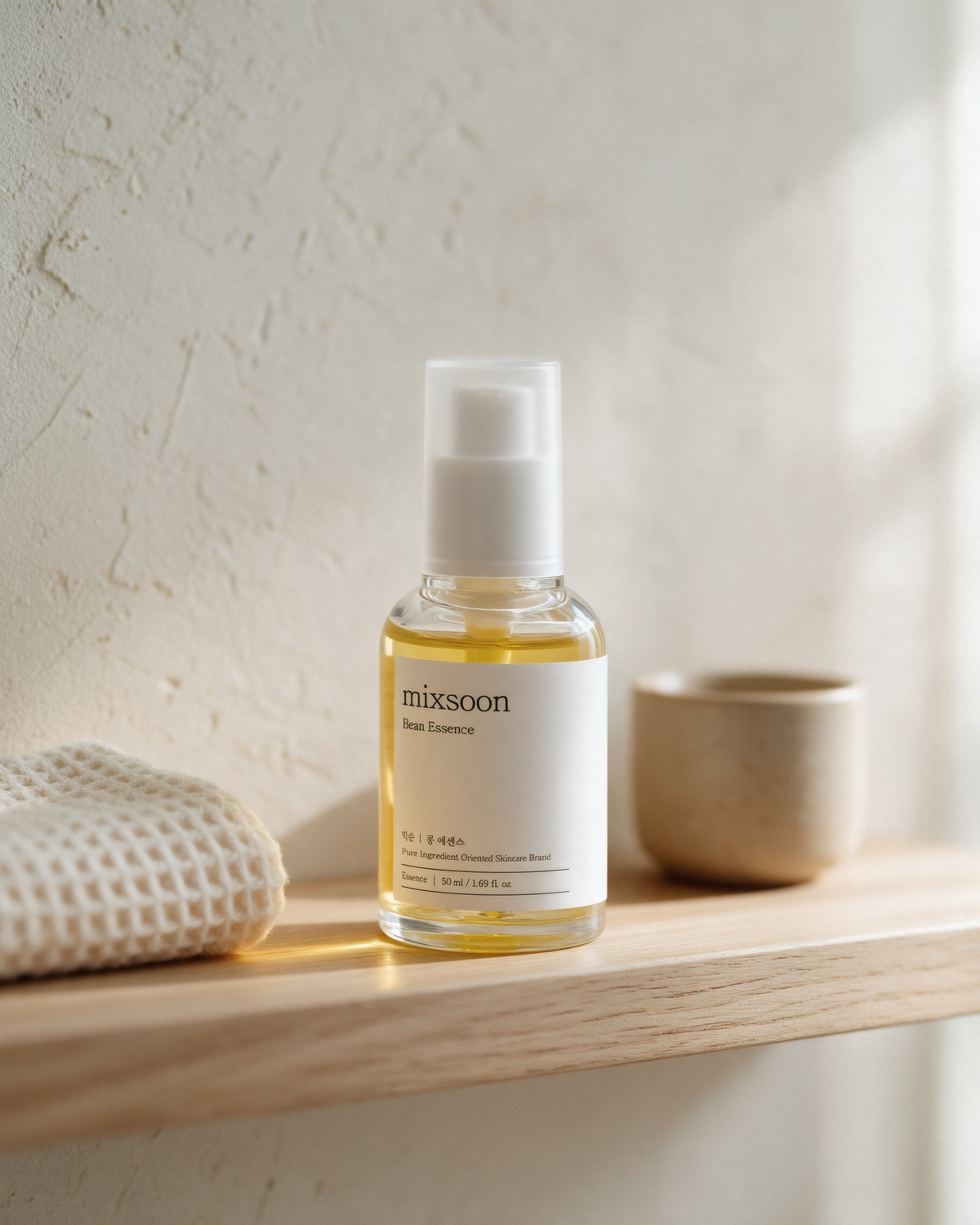Mixsoon Bean Essence on a wooden bathroom shelf beside a waffle towel